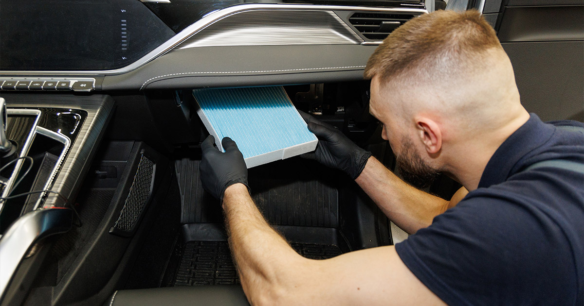 Technician replacing blue cabin air filter in vehicle service bay