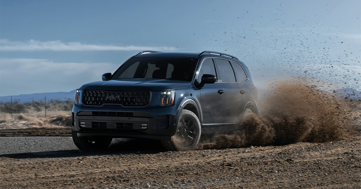 Dark Kia Telluride SUV kicking up dust on dirt road
