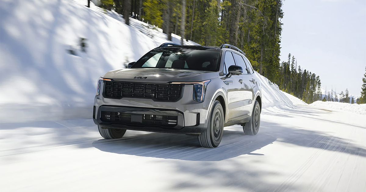 Silver Kia Sorento SUV driving on snowy mountain road