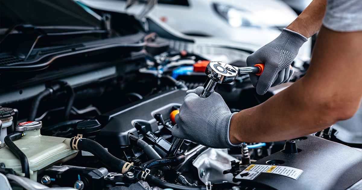 Automotive technician in gloves performing engine maintenance and repairs