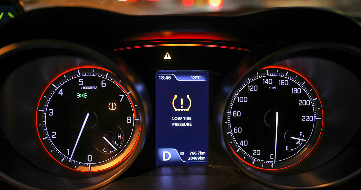 Car dashboard showing tire pressure monitoring system low pressure warning
