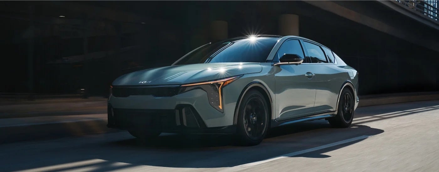 Blue 2025 Kia K4 driving to a Kia dealer
