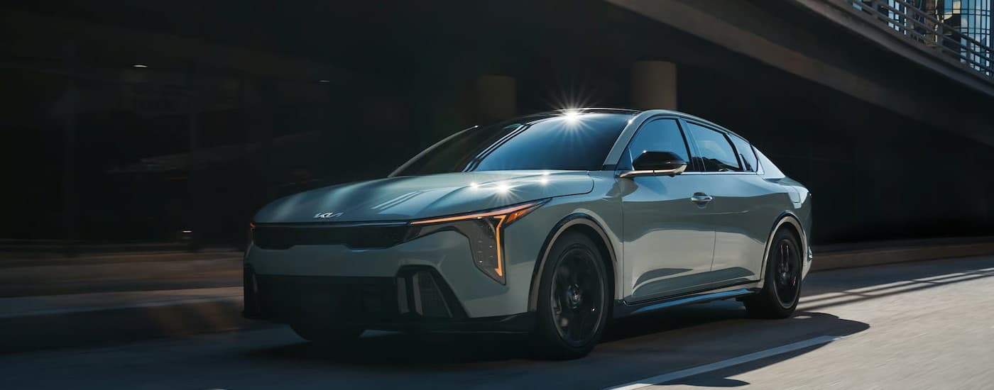 A blue 2025 Kia K4 driving in a city.