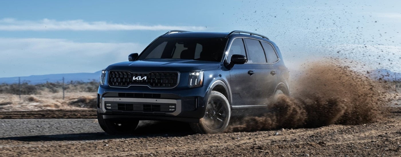 A blue 2025 Kia Telluride for sale kicking up dirt