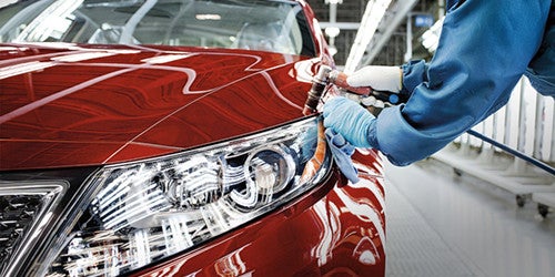 Certified kia service technicians working on a vehicle in a service bay